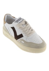 Baskets en cuir blanc avec des accents en daim marron, langue beige et lacets épais beiges. Bout perforé, forme arrondie et semelle texturée.