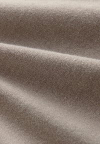 Hellbrauner Textilstoff mit feiner gewebter Textur und subtilen Mustern, die glatte Falten und sanfte Drapierungen zeigen.