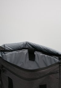 Zaino in tessuto nero con un ampio interno grigio, cuciture rinforzate e chiusura con cinghia. Inclusi taschini con zip sui lati.