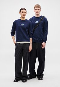 Tengeri kék pulóverek "tommy" logóval, laza, sötét farmernadrággal párosítva. Laza stílus, bordázott mandzsettákkal és kényelmes szabással.