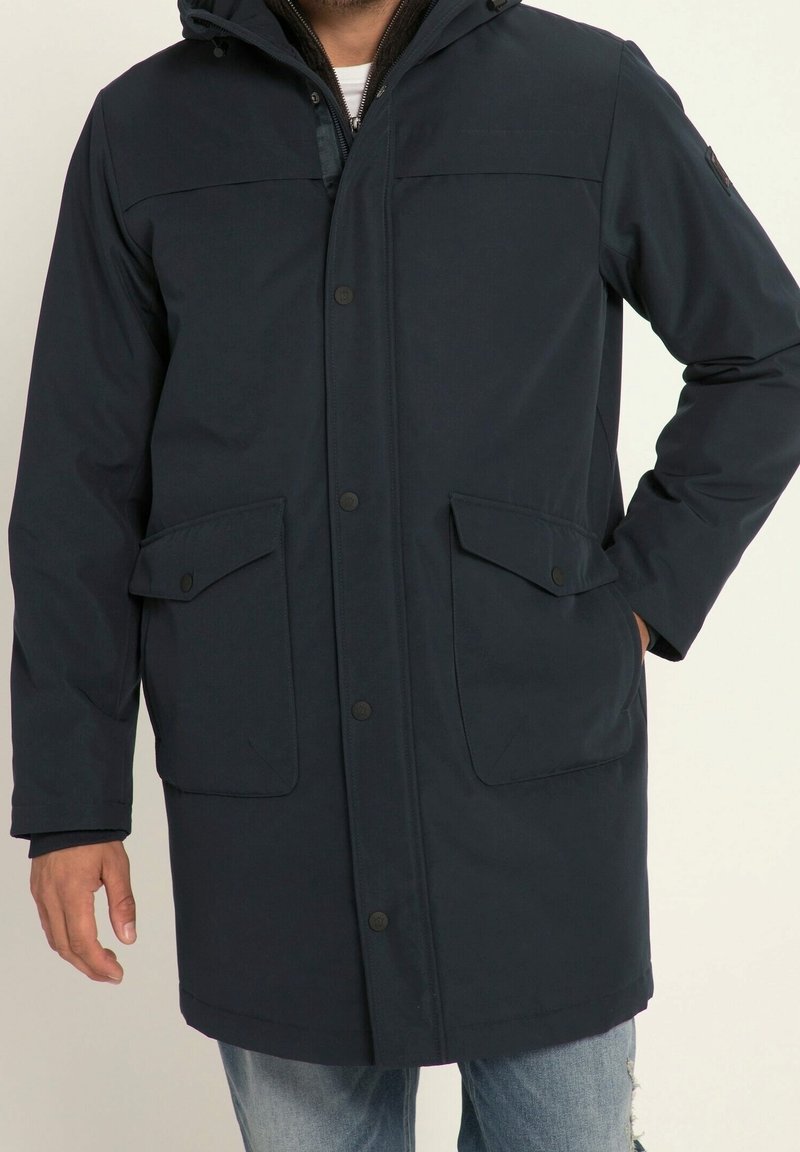 Imperméable marine avec capuche, boutons pression, deux poches avant et tissu légèrement texturé. Coupe décontractée avec une longueur mi-longue.