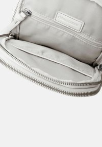 Sacca interna in tessuto grigio con chiusura a zip, dotata di due scomparti aperti e una tasca con zip. Texture liscia con cuciture minime.