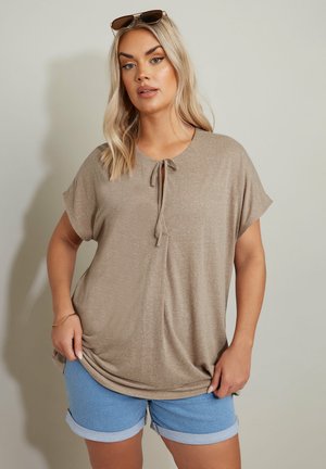 Beige, short-sleeve top with a round neckline and tie detail, paired with light blue denim shorts featuring rolled cuffs. Smooth texture.