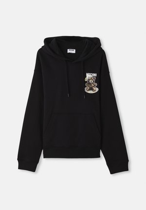 Sweatshirt à capuche noir avec une poche frontale, cordons de serrage, et un design graphique représentant un ours sur une assiette avec le nom de la marque "Moschino."