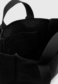 Sac en feutre noir avec une texture douce, doté de deux solides anses en tissu noir et d'une poche intérieure pour l'organisation.