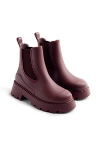 Un paio di stivali Chelsea bordeaux scuro con suole grosse, pannelli laterali elasticizzati e linguette, mostrati su uno sfondo bianco.