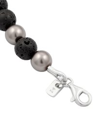 Rocaille en lave et perles métalliques en noir et argent, avec un fermoir et une étiquette marquée 925 en argent. Surface texturée avec des accents lisses.