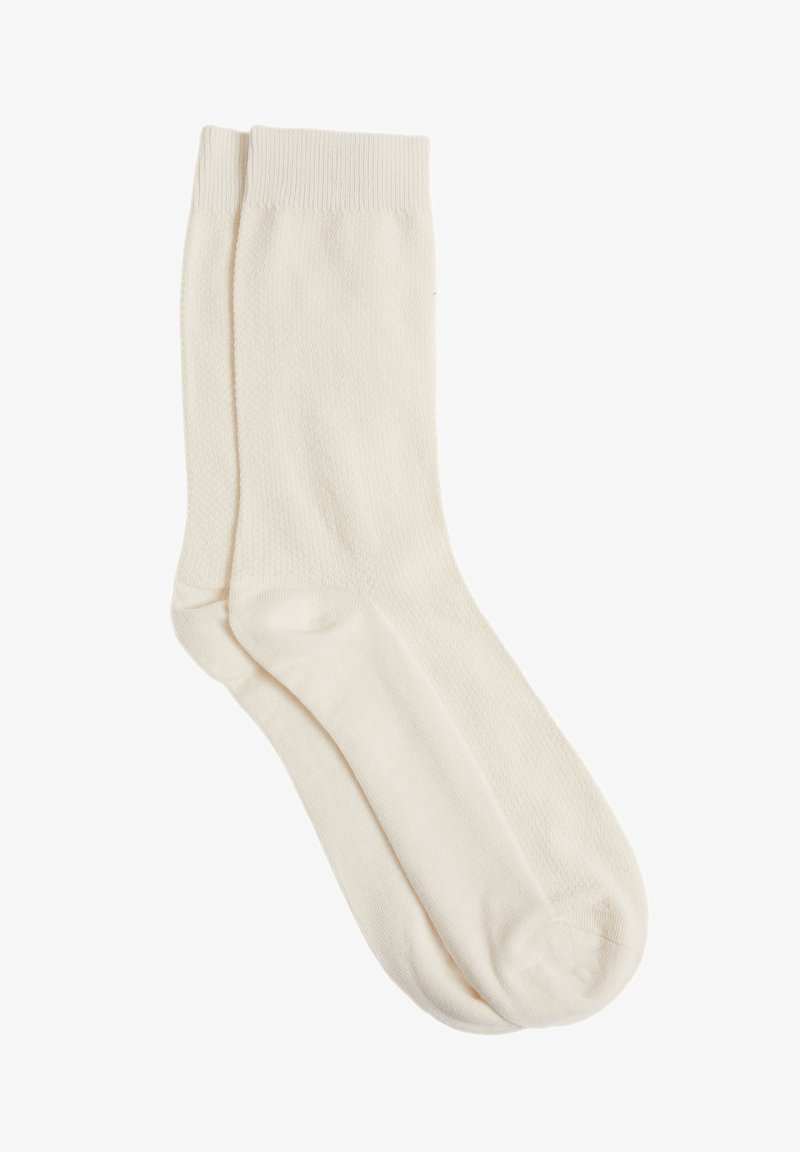 Knielange, cremefarbene Socken aus einem weichen, strukturierten Material mit einem gerippten Bündchen und einem nahtlosen Zehendesign.