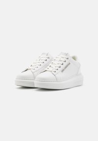 Weißer Sneaker mit einem glatten Lederobermaterial, flachen weißen Schnürsenkeln und einer robusten Plateau-Sohle. Verfügt über ein Markenlogo-Akzent an der Seite.