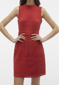 Punainen pitsimekko, jossa on korkea kaula-aukko ja hihaton malli. Sisältää kuvioidun tekstuurin vaakasuorilla raidoilla. Tiukka vyötärö ja A-linjainen hame.