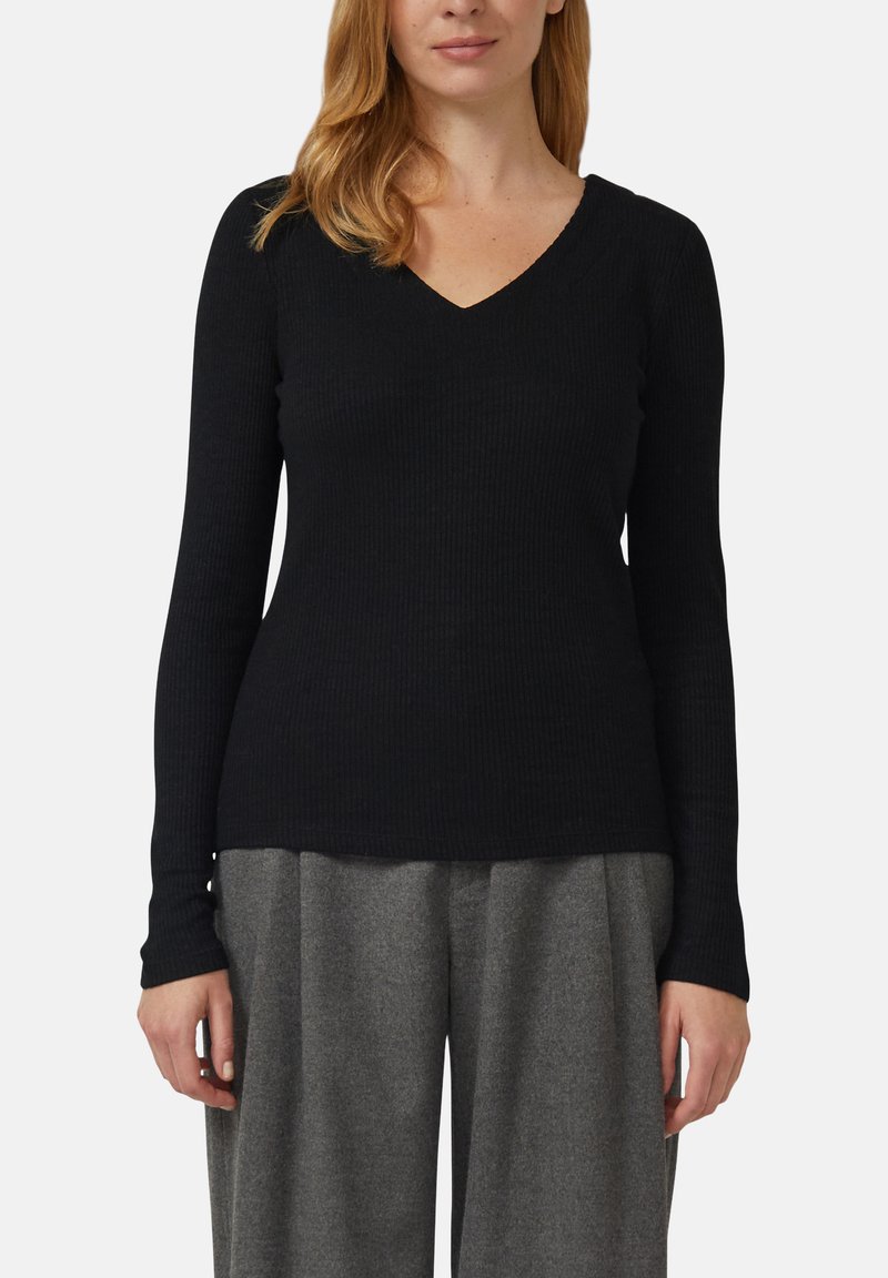 Czarna prążkowana bluzka z długim rękawem i dekoltem w kształcie litery V. Gładka faktura, dopasowany krój i delikatne rozszerzenie u dołu, zestawiona z szarymi spodniami o szerokich nogawkach.
