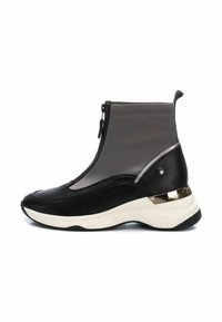 Zapatilla negra y gris de caña alta con un brillante acento plateado, paneles texturizados en negro y un cierre con cremallera para poner y quitar fácilmente.