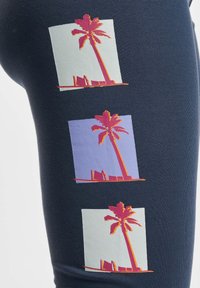 Marine leggings met drie palmboomgraphics in roze, oranje en pastelkleurige vierkanten, met een textuurpatroon.