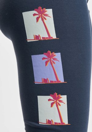 Marine leggings met drie palmboomgraphics in roze, oranje en pastelkleurige vierkanten, met een textuurpatroon.