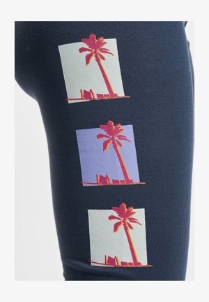 Leggings en azul marino con tres gráficos de palmeras en rosa, naranja y cuadrados en tonos pastel, con un diseño de tela texturizada.