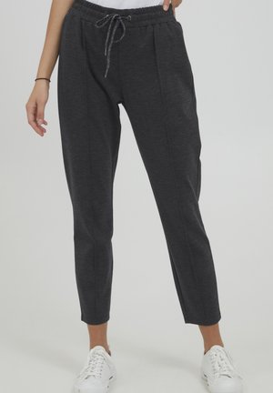 Dark gray, fitted sweatpants with a drawstring waistband and cuffs, featuring two vertical seams on front legs. Worn with white sneakers.