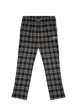 Pantaloni del pigiama a quadri in bianco e nero con vita elastica e logo Lonsdale sulla coscia anteriore, posati in piano.