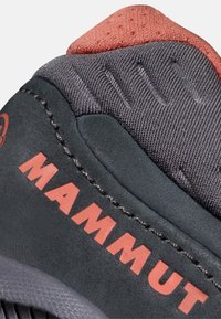 Punta di scarpa sportiva nera e grigia con tessuto testurizzato, colletto imbottito e marchio "MAMMUT" rosso in evidenza sul lato.