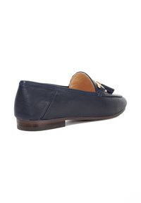 Navy leather loafers with a flat heel, featuring a decorative tassel and a stitched design on the upper. Smooth texture with a slip-on style.