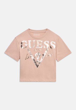 Light pink short-sleeve t-shirt with metallic silver "GUESS EST. 1981 Los Angeles" logo and triangular design on front.