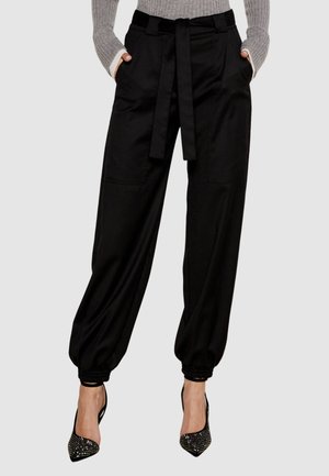 Pantaloni tapered neri con vita regolabile, dotati di due tasche frontali e polsini elasticizzati. Tessuto liscio con un fit rilassato.
