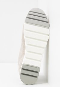 Sandaalin pohja, jossa on vaaleanbeige väri ja valkoisia sekä harmaita kumipainanteita, joissa on vaakasuoria uria. Koko 37 on painettu lähelle keskikohtaa.