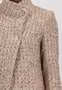 Wollen blendjas in crèmekleur en bruin, met een hoge kraag en twee grote knopen. Textiel met een geweven patroon.