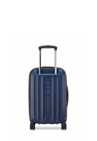 Maleta rígida en azul marino con textura de surcos verticales, manija telescópica plateada, detalles en marrón y cuatro ruedas para mayor movilidad.