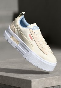 Puma Plattform-Sneaker aus cremefarbenem Leder mit strukturierten Akzenten, hellblauer Innenausstattung und weißer Gummisohle mit Logo-Details.