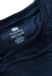 Marineblå uld T-shirt med rund hals, der har en glat tekstur og et mærke, der angiver størrelse 'Medium' og vaskeanvisninger.