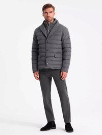 Doudoune grise avec un col châle, des boutons à l'avant et deux poches latérales ; associée à un pantalon gris et des bottines noires.
