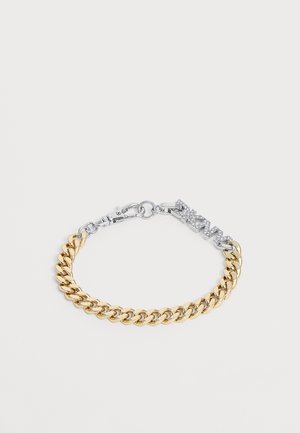 Guldtonet kædearmbånd med en sølvtonet charm med teksten "DKNY", indlagt med små klare krystaller og lukning med krabbeled.