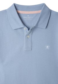 Jasnoniebieska koszulka polo z teksturowanej tkaniny, z dwoma guzikami i białym logo na klatce piersiowej. Kołnierzyk ma różowy akcent od wewnętrznej strony.