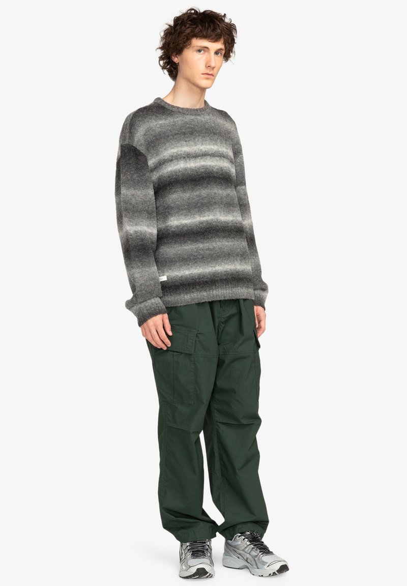 Grijs gestreepte wollen trui met een ronde hals, gecombineerd met donkergroene cargo broek en grijze sportschoenen. Casual outfit met textuurcontrast.
