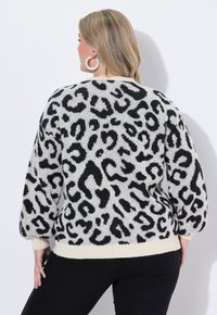 Jersey de leopardo en crema y negro, textura de punto, corte relajado, puños y dobladillo acanalados, mostrado desde la parte posterior con un fondo liso.