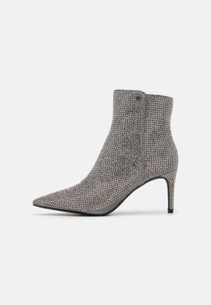 Spitz zulaufender Knöchelstiefel, bedeckt mit silbernen Strasssteinen, mit mittelhohem, schlankem Absatz, seitlichem Reißverschluss und abgerundetem oberen Rand.