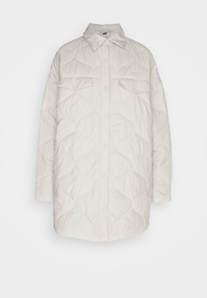 Quiltet cremejakke med knaplukning foran, to brystlommer og spredt krave. Fremstillet af blødt, letvægtsstof med et tekstureret mønster.