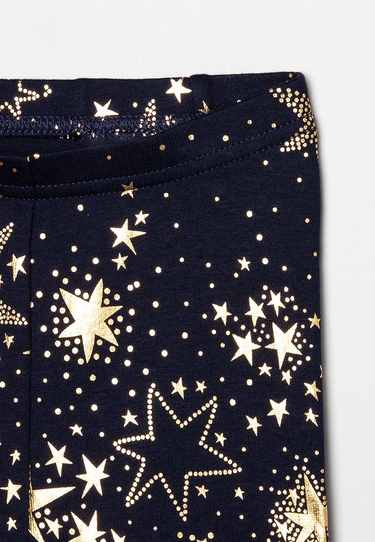 Leggings en tissu bleu marine ornés de motifs d'étoiles et de points dorés, avec une texture douce et extensible et une taille élastique pour un ajustement confortable.
