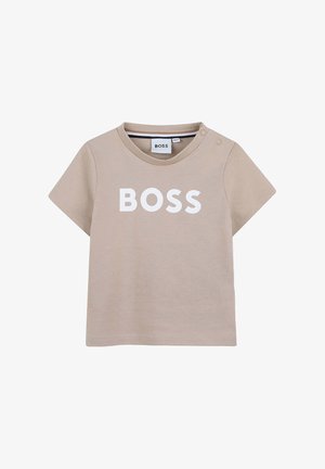 Beige short-sleeve toddler t-shirt with white "BOSS" text on front and two small snap buttons on left shoulder.