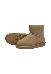 Tan suède enkelboots met een zachte textuur, ronde neus en een platte rubberen zool met een gemarmerd grippatroon. Accentuerend met een zijnaad.