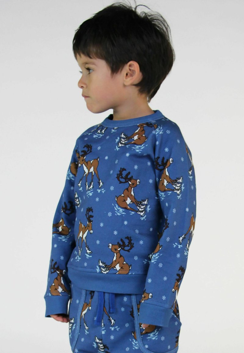 Zila sporta krekls ar brieža slidošanas motīvu, izgatavots no mīksta auduma, ar apaļu kakla izgriezumu un pievilktiem piedurkņu un apakšmalas galiem. Saskaņots ar atbilstošām biksēm.