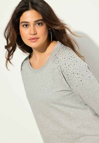 Maglione grigio a maniche lunghe con scollo rotondo e dettagli in strass sulle spalle, realizzato in un tessuto morbido e testurizzato per garantire comfort.