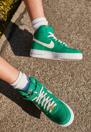 Baskets montantes vertes en matériau texturé, avec des lacets blancs et le logo Swoosh, comportant un col rembourré et une boîte à orteils perforée.