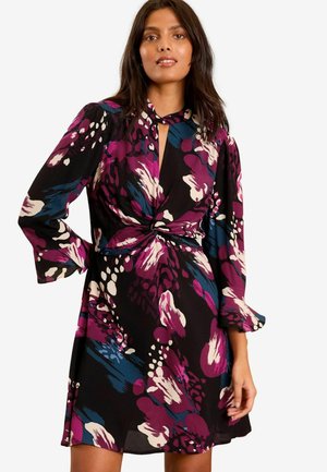 Rochie florală neagră cu modele vibrante în roz, albastru și alb. Prezintă un detaliu răsucit la talie și mâneci lungi, evazate.