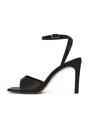 Sandale noire à talon haut avec bout ouvert, large bride avant, fine bride à la cheville avec boucle argentée, et talon aiguille élancé.