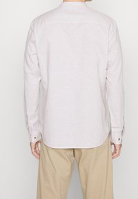 Camicia button-up rosa chiaro con maniche lunghe e un orlo arrotondato. Presenta colletto a punta e polsini con bottoni. Tessuto morbido e testurizzato.