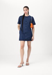 Denimkleit sirge lõikega, lühikeste varrukatega ja nupuvajutusega ees. Kombineeritud väikese oranži kotiga ja beežide kontsakingadega.