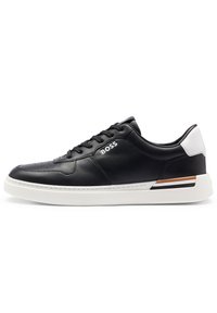 Sneaker in pelle nera con suola bianca, dotato di punta arrotondata, stringhe frontali e accenti a contrasto sul tallone e sul lato. Logo del brand visibile.