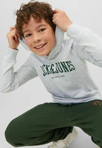 Sudadera gris con letras verdes y un bolsillo frontal, acompañada de pantalones de chándal verde oscuro. La sudadera tiene una capucha forrada y puños acanalados.