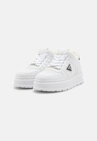 Sneakers platform bianchi in pelle sintetica con una finitura testurizzata, dotate di un morbido rivestimento in pelliccia sintetica e un accentuazione decorativa a triangolo.